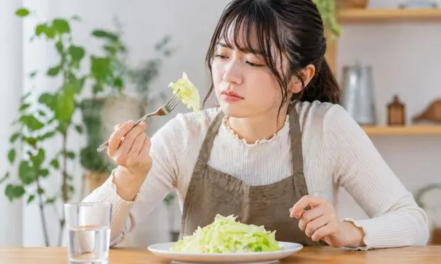 キャベツが苦い原因を気にしてサラダを確認する女性のイメージ